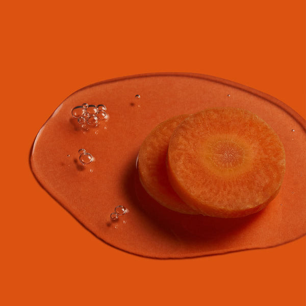 Rondelles de carotte dans une goutte d'huile, caroténoïdes naturels, sur fond orange