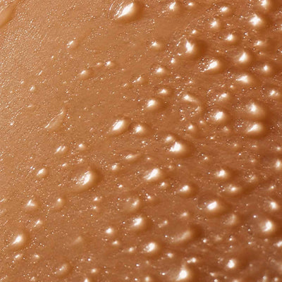 Peau dorée perlée de gouttes d'eau en très gros plan, hydratation profonde de la peau