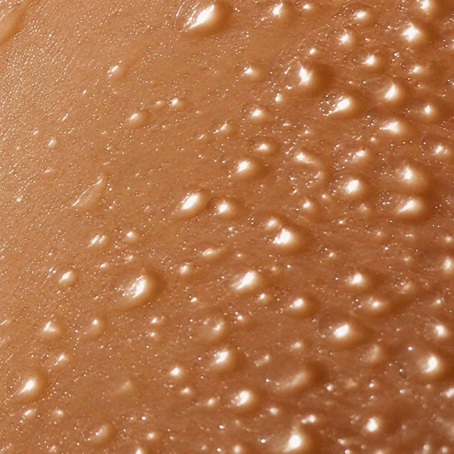 Peau dorée perlée de gouttes d'eau en très gros plan, hydratation profonde de la peau