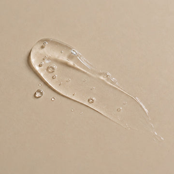Trait de sérum gel transparent à l'acide hyaluronique étalé sur fond beige