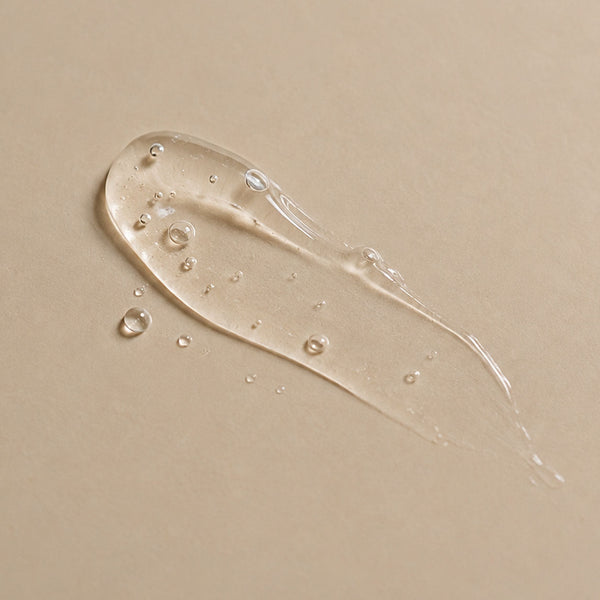 Trait de sérum gel transparent à l'acide hyaluronique étalé sur fond beige