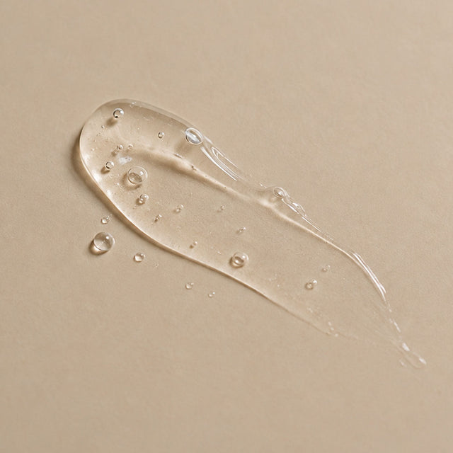 Trait de sérum gel transparent à l'acide hyaluronique étalé sur fond beige