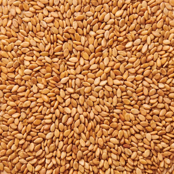 Graines de sésame dorées en plein cadre, matière première de l'huile de sésame cosmétique
