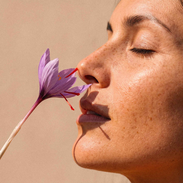 Femme respirant une fleur de safran les yeux fermés, rituel ayurvédique au quotidien