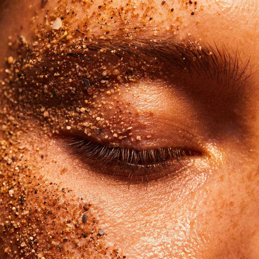 Œil fermé saupoudré de grains de gommage dorés sur la paupière et le sourcil