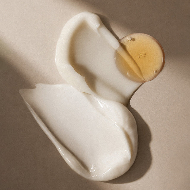 Trait de crème et goutte d'huile dorée côte à côte sur fond beige, choisir entre crème et huile visage