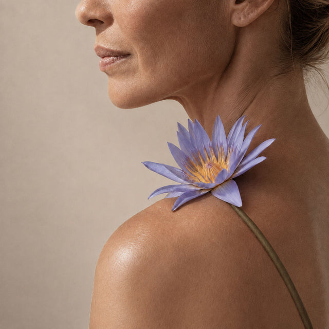 Fleur de lotus bleu posée sur l'épaule d'une femme de profil, esprit slow beauty