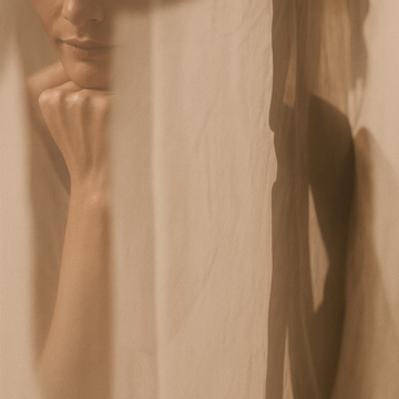 Silhouette féminine derrière un voilage baigné de lumière douce, illustrant l’intimité, la sensibilité et la vision slow beauty de Just avant.
