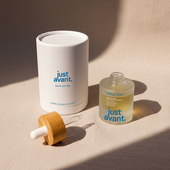 Packshot du sérum visage Lotus Bleu Just Avant avec flacon en verre givré, pipette en verre à bouchon en bois et étui cylindrique blanc, présenté sur fond textile clair.